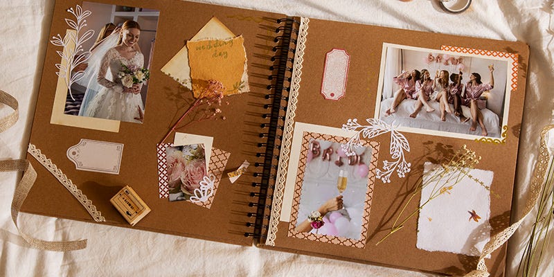 Wedding photos are laid out and stuck down in a scrapbook with neutral tones. White hand-drawn flowers are alongside the images.