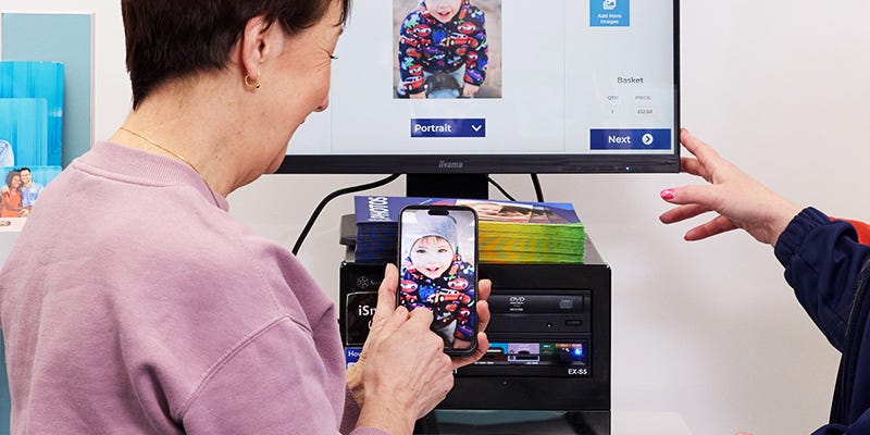 A female customer printing photos from iPhone at a Max Spielmann store.