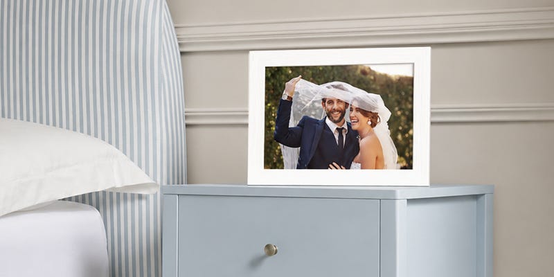 A framed photo on a blue bedside table of a happy couple on their wedding day.