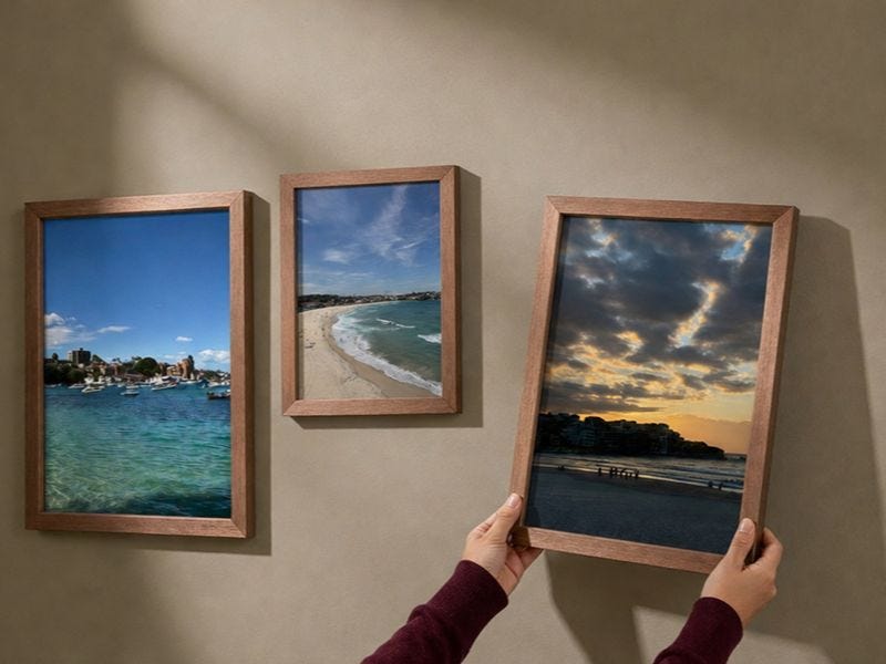 a framed photo print being hung on a wall next to two more framed photo prints